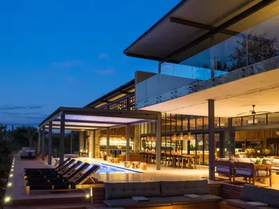 a large glass house with a swimming pool at night at Luxury Family Villa in Greater Kruger in Hectorspruit