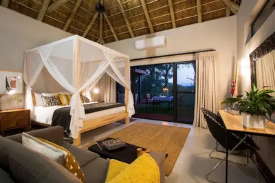 a bedroom with a canopy bed and a living room at Moya Safari Villa in Hoedspruit