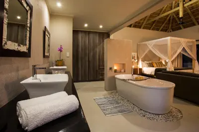 a bathroom with a tub and a sink and a bed at Moya Safari Villa in Hoedspruit
