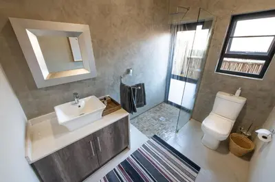 a bathroom with a sink and a toilet and a mirror at Moya Safari Villa in Hoedspruit