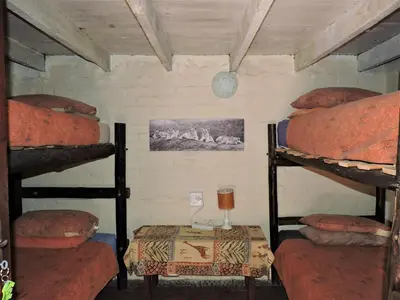 a room with three bunk beds and a table at Kruger Inn Backpackers in Marloth Park