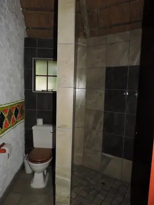 a bathroom with a toilet and a glass shower at Kruger Inn Backpackers in Marloth Park