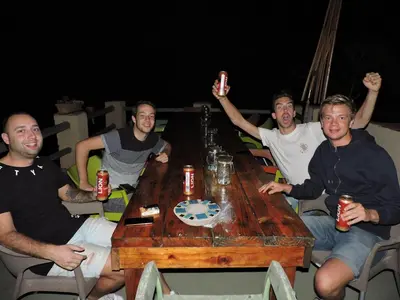 a group of men sitting around a wooden table at Kruger Inn Backpackers in Marloth Park