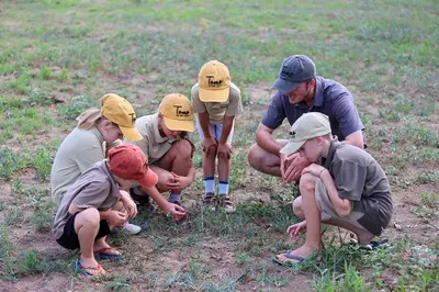 a group of people crouching in a field at Tomo Safari Lodge in Hoedspruit