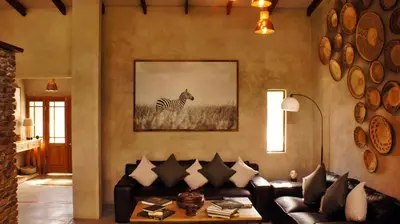 a living room with a couch and a zebra picture on the wall at Dream of Africa Bush Lodge in Marloth Park