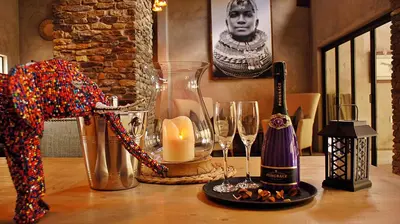 a table topped with glasses and a bottle of wine at Dream of Africa Bush Lodge in Marloth Park