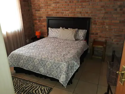 a bedroom with a bed and a brick wall at Eagle's Crest in Marloth Park
