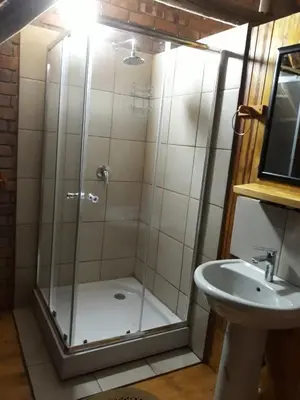 a shower with a glass door next to a sink at Eagle's Crest in Marloth Park