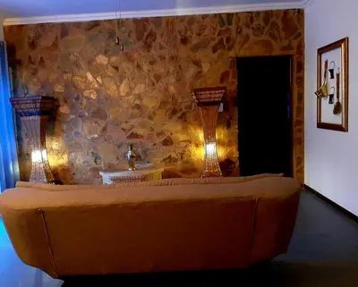 a living room with a couch and a stone wall at Rocky Hollow Lodge in Pretoria