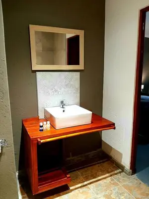 a bathroom with a white sink on a wooden counter at Rocky Hollow Lodge in Pretoria