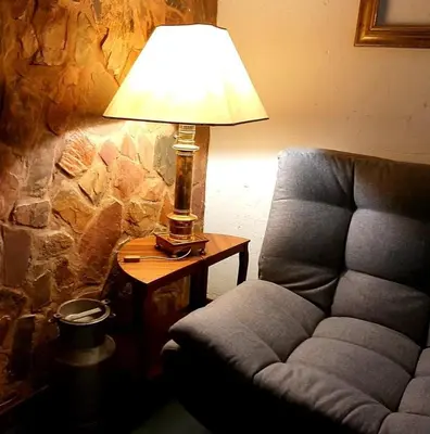 a lamp sitting on a table next to a chair at Rocky Hollow Lodge in Pretoria
