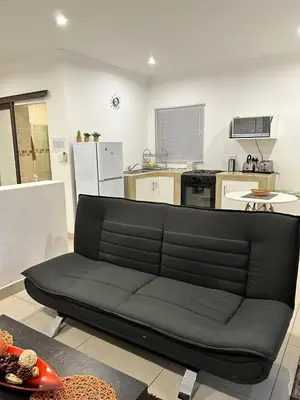 a black couch in a living room with a kitchen at Sweet Home Alibama in Nelspruit