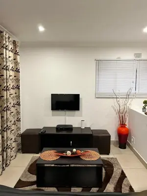 a living room with a tv and a table at Sweet Home Alibama in Nelspruit