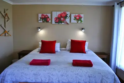 a bedroom with a white bed with red pillows at Forest View Cabins in Tzaneen