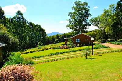 a garden with a house in the middle of a field at Forest View Cabins in Tzaneen