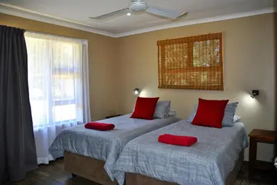 a bedroom with two beds with red pillows at Forest View Cabins in Tzaneen
