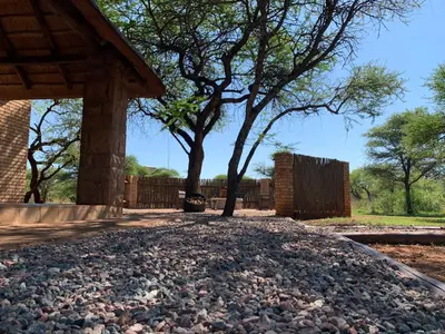 a gravel driveway with two trees and a fence at Makhato Bush Lodge 111 in Bela-Bela