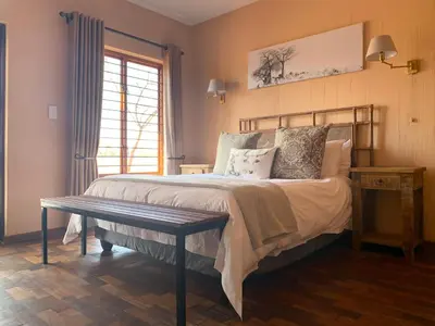 a bedroom with a bed with a bench and a window at Makhato Bush Lodge 111 in Bela-Bela