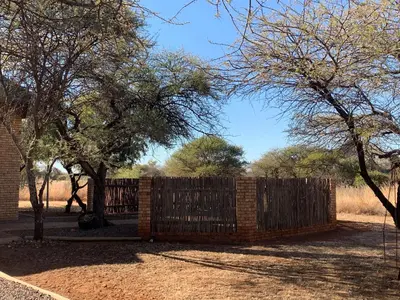 a wooden fence in a yard with trees at Makhato Bush Lodge 111 in Bela-Bela