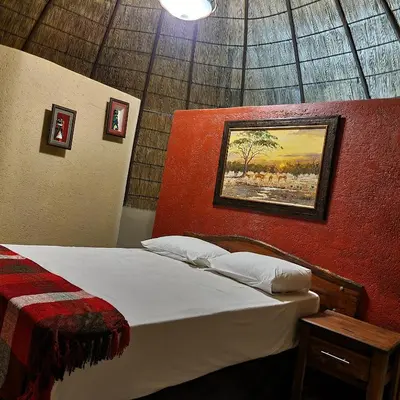 a bedroom with a bed and a painting on the wall at Mountain Aloe Den in Barberton