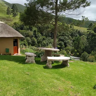 a picnic table and bench in a field with a house at Mountain Aloe Den in Barberton