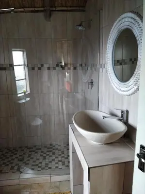a bathroom with a tub and a sink and a mirror at Mountain Aloe Den in Barberton
