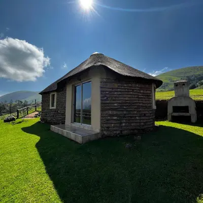 a small brick house with a grass roof at Mountain Aloe Den in Barberton