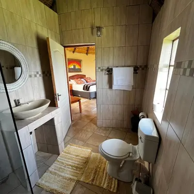 a bathroom with a toilet and a sink and a bed at Mountain Aloe Den in Barberton