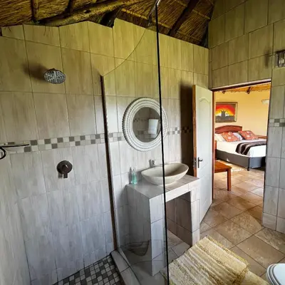 a bathroom with a shower and a sink and a bed at Mountain Aloe Den in Barberton