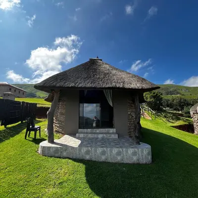 a small hut with a grass roof on the grass at Mountain Aloe Den in Barberton