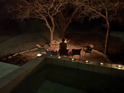 a man sitting on a patio at night at Mopani Villa in Marloth Park
