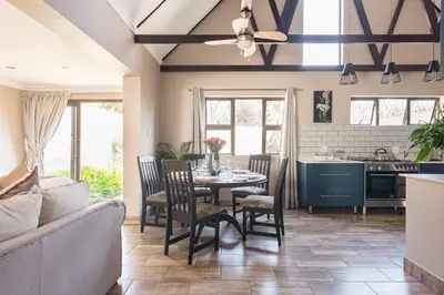 a kitchen and living room with a table and chairs at Ginger Barn Retreat - 1km from Menlyn in Pretoria