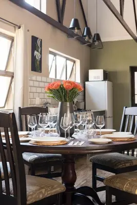 a table with wine glasses and a vase with flowers on it at Ginger Barn Retreat - 1km from Menlyn in Pretoria