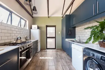 a kitchen with blue cabinets and a washer and dryer at Ginger Barn Retreat - 1km from Menlyn in Pretoria