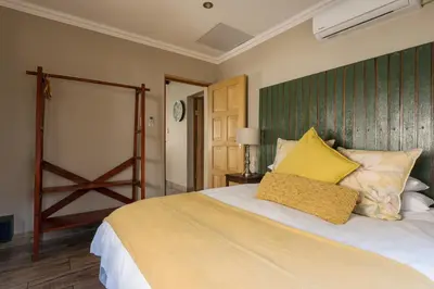 a bedroom with a large bed with yellow pillows at Ginger Barn Retreat - 1km from Menlyn in Pretoria