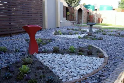 a garden with rocks and a red sculpture at La Bendicion in Witbank