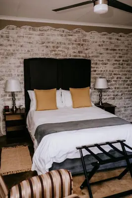 a bedroom with a large bed with a brick wall at La Bendicion in Witbank