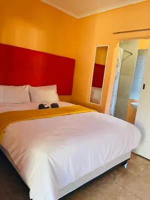 a bedroom with a large bed with a red headboard at Maite Villa Lodge in Thohoyandou