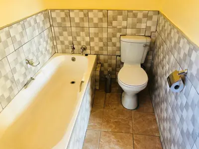 a bathroom with a toilet and a bath tub at Maite Villa Lodge in Thohoyandou