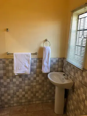 a bathroom with a sink and white towels at Maite Villa Lodge in Thohoyandou