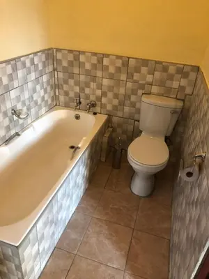 a bathroom with a toilet and a tub and a toilet paper roll at Maite Villa Lodge in Thohoyandou