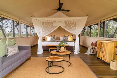 a bedroom in a tent with a bed and a couch at Mdluli Safari Lodge in Hazyview