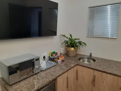 a kitchen counter with a microwave and a sink at 64 on Malabor in Pretoria