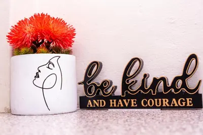 a flower in a mug with a sign that reads be kind and have courage at High Court Self Catering Apartments in Nelspruit