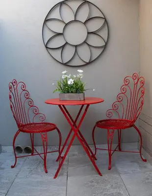 a red table and two chairs with a table and a mirror at High Court Self Catering Apartments in Nelspruit