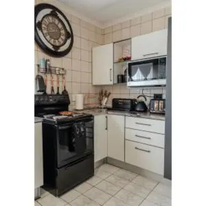 a kitchen with white cabinets and a black oven at High Court Self Catering Apartments in Nelspruit