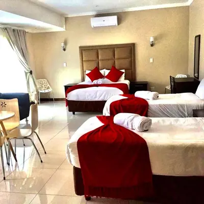 a hotel room with three beds with red sheets at Aqua Stone guest house in Nelspruit