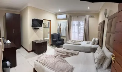 a hotel room with two beds and a chair at Aqua Stone guest house in Nelspruit