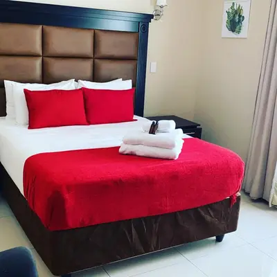 a bedroom with a large bed with red pillows at Aqua Stone guest house in Nelspruit