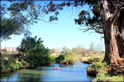 a person kayaking on a river with a tree at Aqua Terra Guest House in Lydenburg